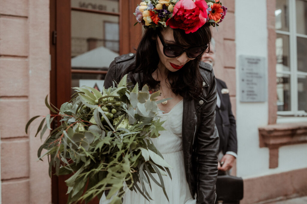 Photo de la mariée avec un perfecto noir, une couronne de fleurs dans les cheveux et sa robe de mariée, en Alsace près de Colmar