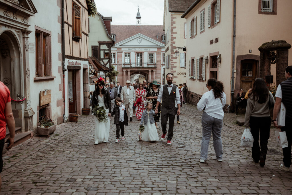 Les mariées, leurs enfants et leurs invités dans les rues de Riquewihr en Alsace près de Colmar rejoignent le restaurant pour une cérémonie laïque