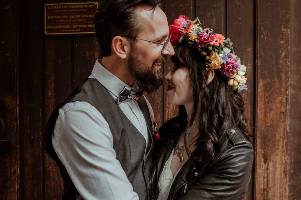 Photo de couple des mariés qui rient ensemble. La mariée a une couronne de fleurs sur la tête et un perfecto noir