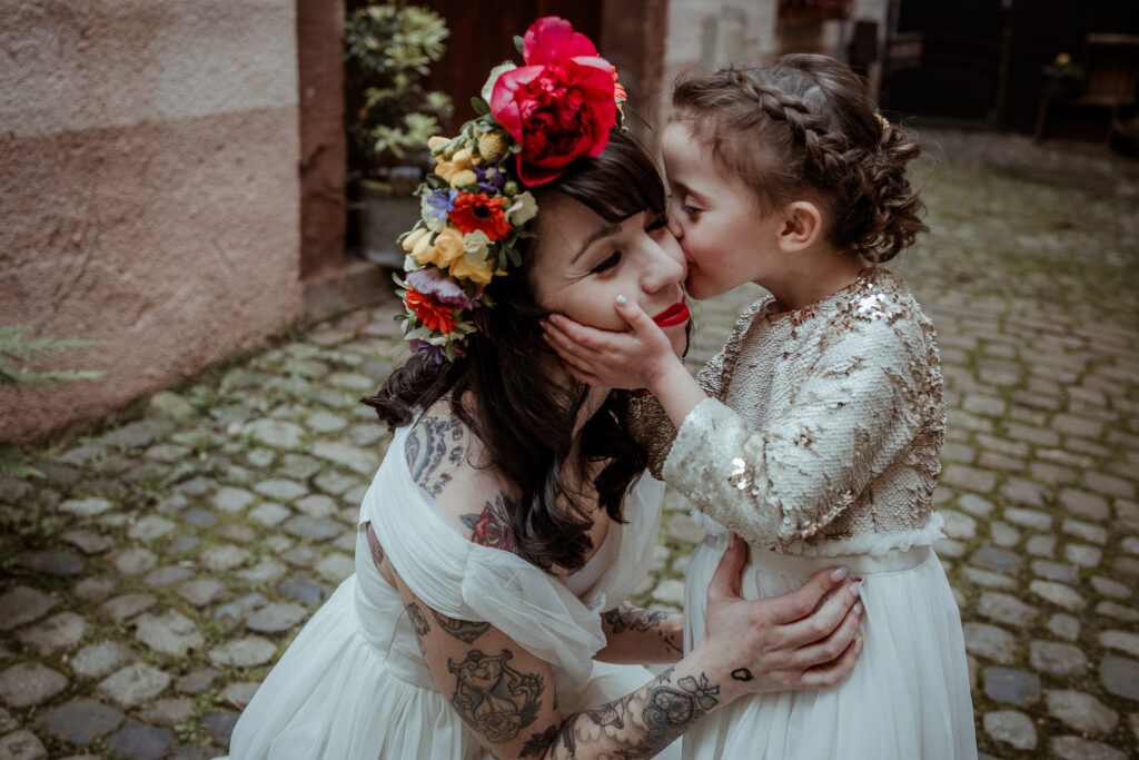 Mariée dans sa robe et avec sa couronne de fleurs sur la tête, avec sa fille en robe blanche pour le mariage dans ses parents dans les rues de Riquewihr près de Colmar en Alsace